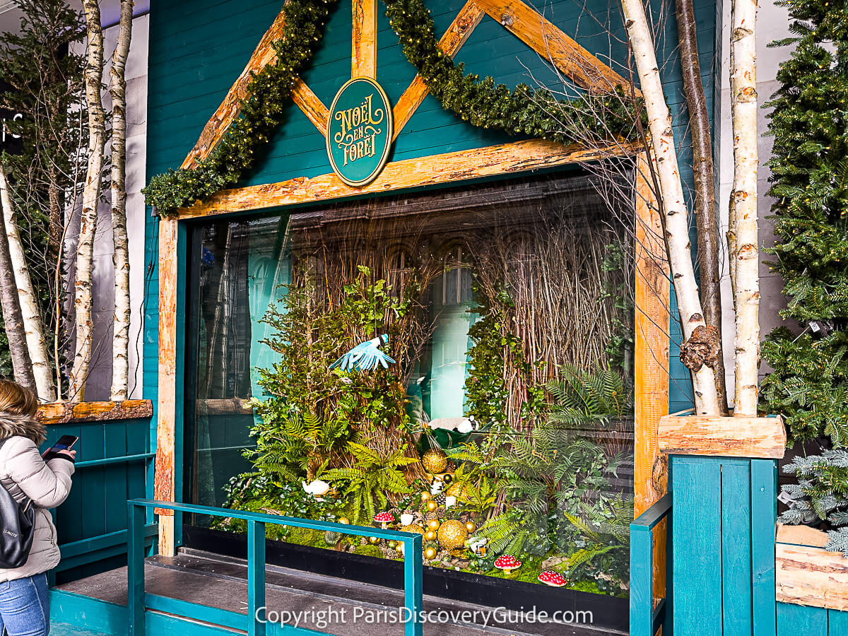 An animated bird flies back and forth forver the forest floor strewn with golden balls and jeweled mushrooms in this Christmas window at BHV Marais