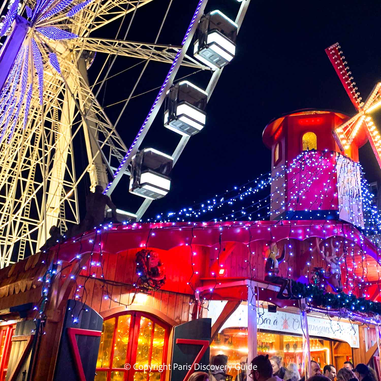 A Champagne Bar topped by a replica of the windmill at Moulin Rouge at the Tuileries Garden Christmas Market, and the giant Ferris wheel