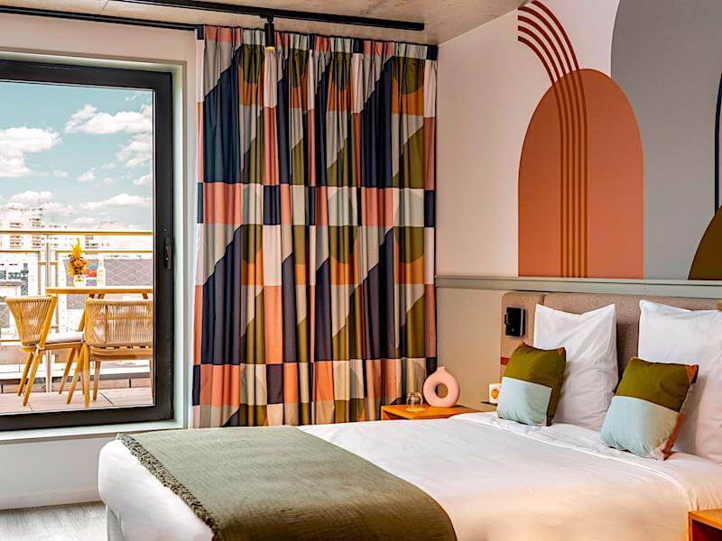 Guest room with balcony and city rooftop views at Hotel La Belle Ville Guest room with balcony and city rooftop views at Hotel La Belle Ville