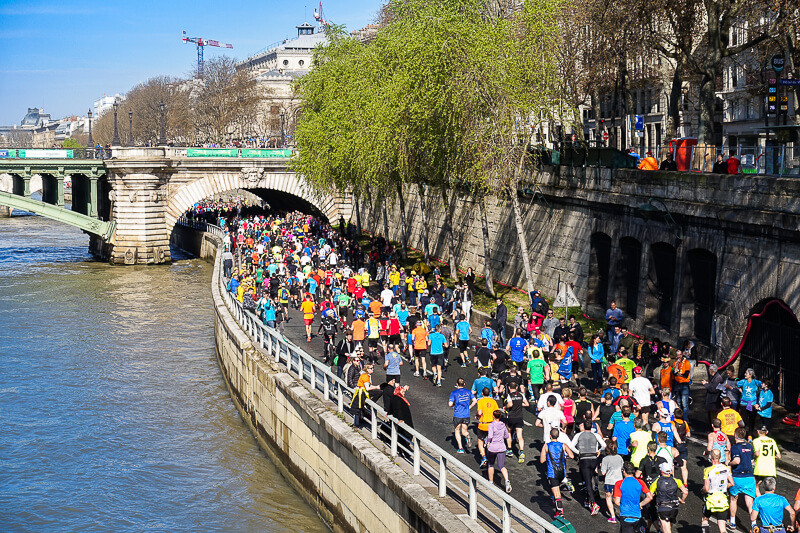 Paris Marathon runners along the Seine River and Notre Dame Bridge