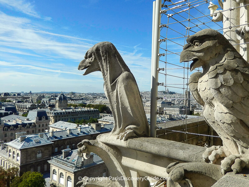 Gorgoyles peering out over the rooftops of Paris, with Sacre Coeur visible on the skyline  