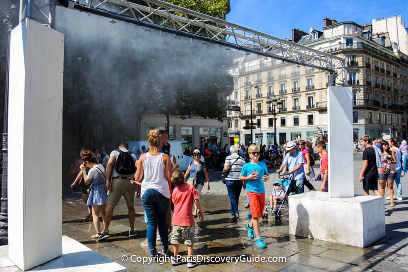Shoppers from nearby rue de Rivoli walk over to cool off under the mist fountain - another popular feature at the Paris City Hall "beach" Shoppers from nearby rue de Rivoli walk over to cool off under the mist fountain - another popular feature at the Paris City Hall "beach"