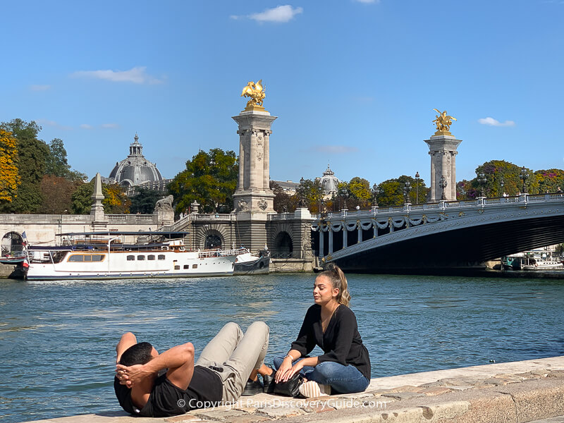 Couple sitting on a wall overlooking the Seine River and the Right Bank