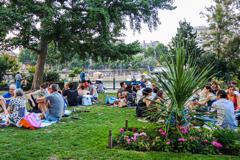 Parisians relaxing on Square de Vert-Galant overlooking the Seine River near Sainte Chapelle