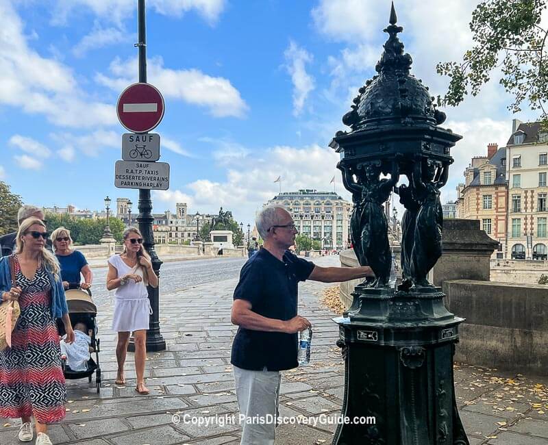 Refilling a water bottle at a Wallace Fountain next to the Pont Neuf Bridge on a steamy hot July day