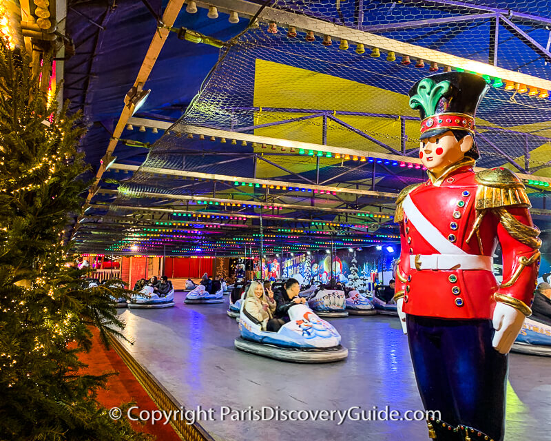 Larger-than-life-size toy soldier standing guard over bumper cars at Tuileries Xmas Market