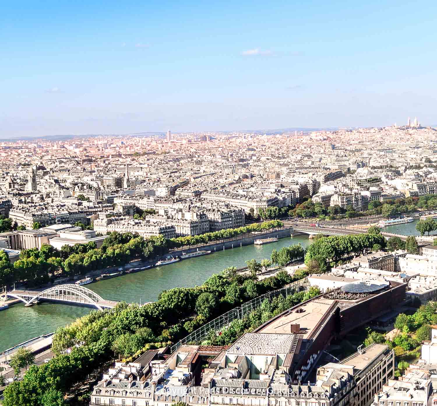 Paris skyline seen from the Eiffel Tower's Second Level observation deck, with Pont Debilly bridge and other nearby attractions easy to spot and Sacre Coeur and Montmartre visible on the skyline