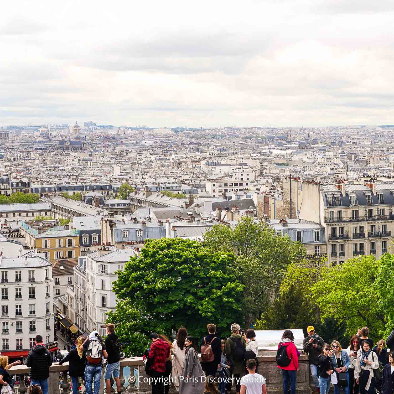 Sacre Coeur visitors on the terrace overlooking the Paris skyline