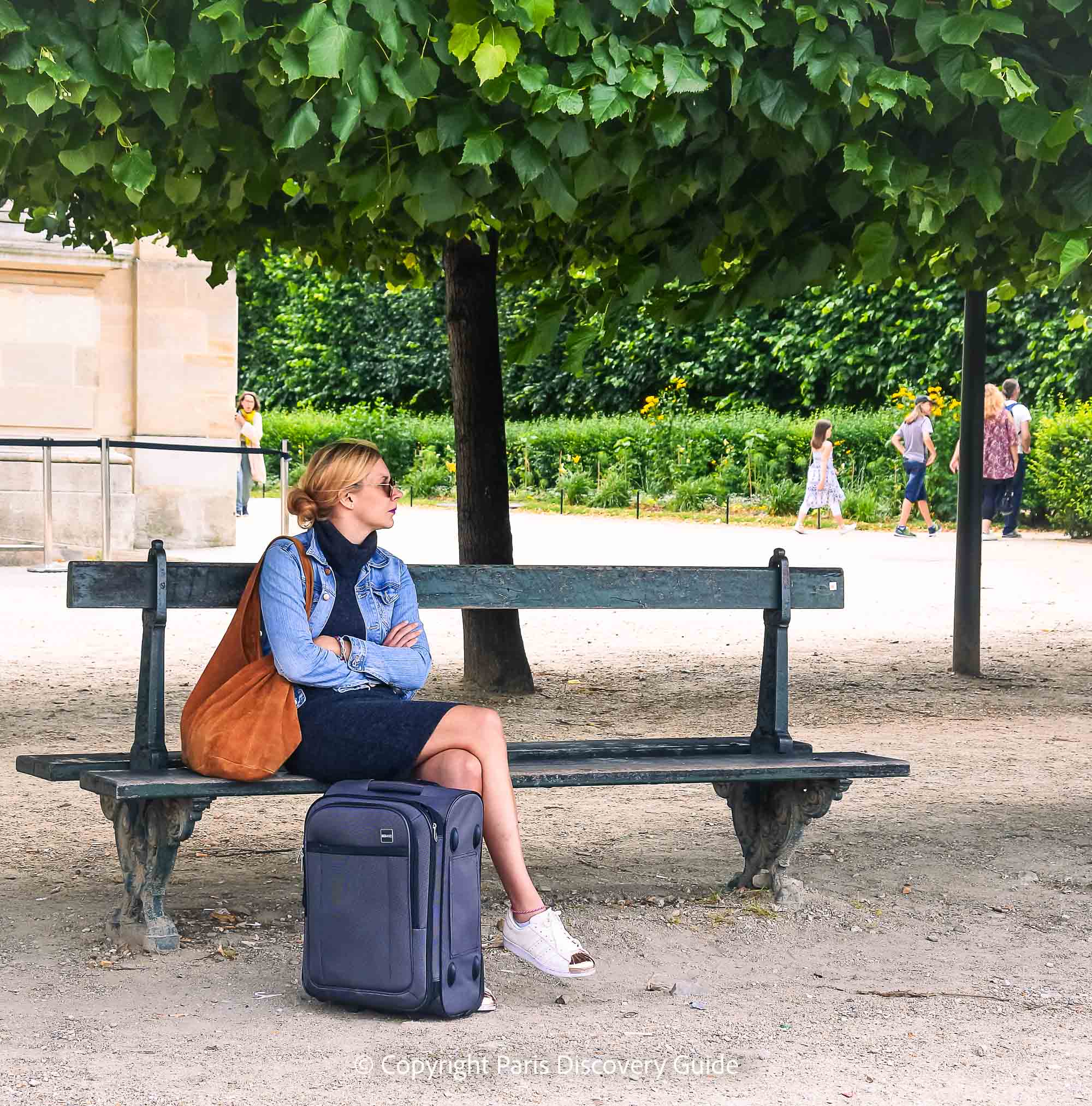 Sitting in a park with a suitcase in Tuileries Garden Sitting in a park with a suitcase in Tuileries Garden