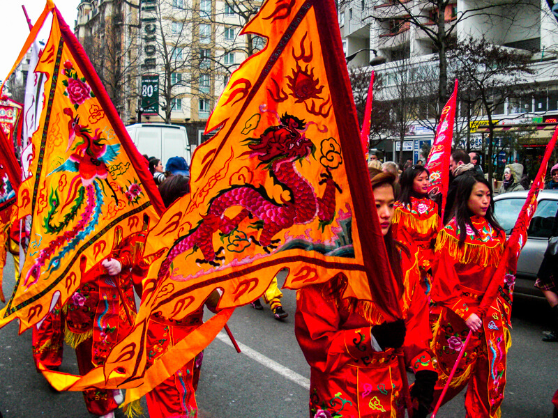 Marchers carrying flags in Paris Chinese New Year Parade