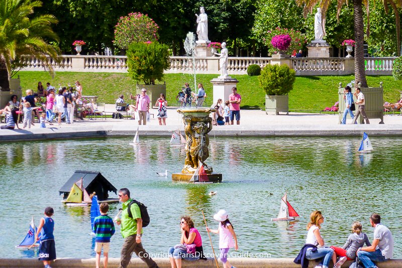 Children "sailing" wooden boats in Luxembourg Garden