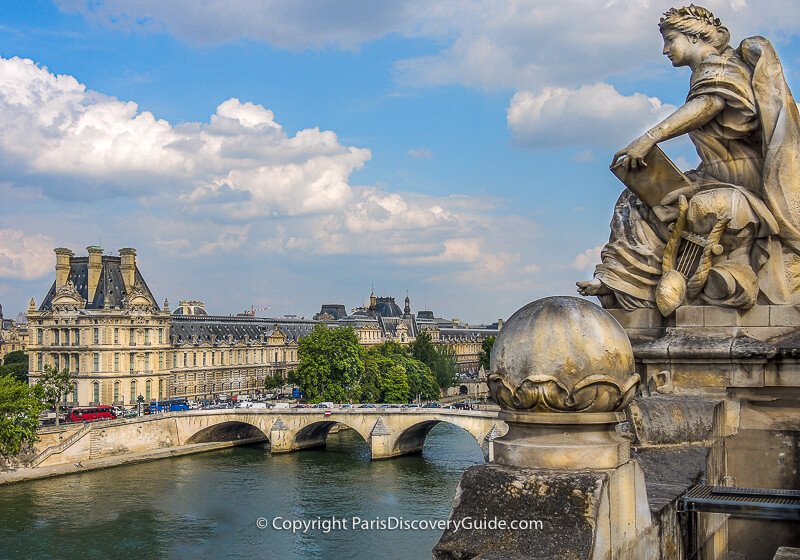 Giant statue perched on the edge of the Summer Terrace overlooking the Seine River, Pont Royal, and the Louvre