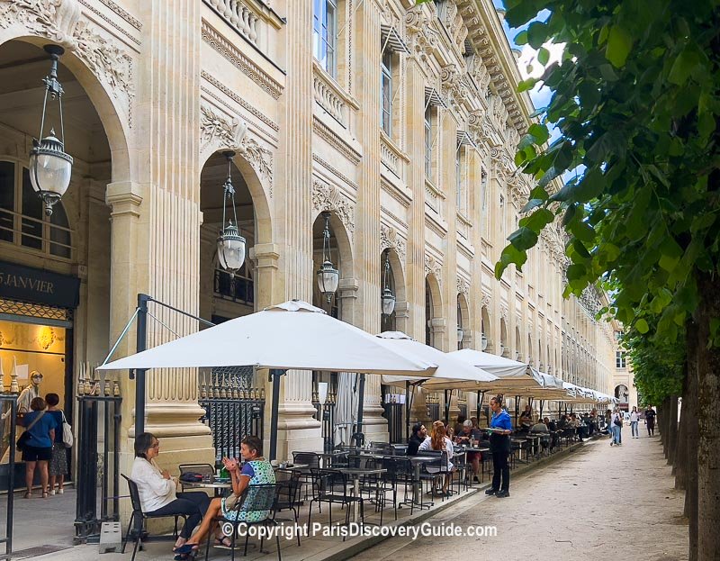 Covered arcade at Palais Royal, with boutiques and bistros lining the interior passage and dining along the terrace across from double rows of lime trees surrounding Palais Royal's formal garden (not shown in this photo)