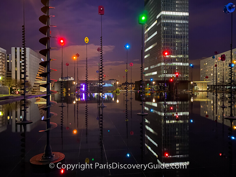 Colored lights at the Takis Bassin (reflecting pool), with the Esplanade de La Defense Metro station in the background